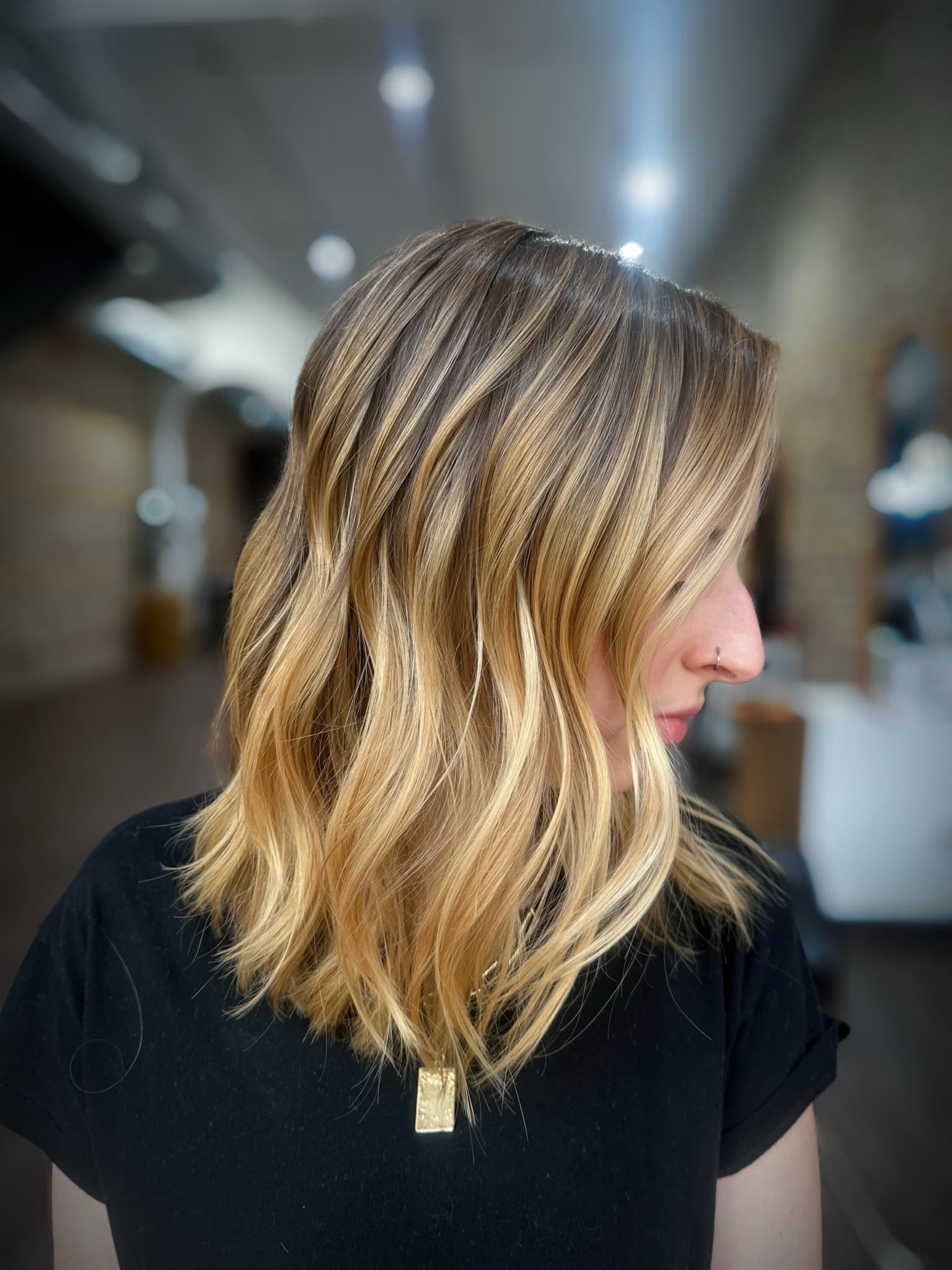 Close view of a golden blonde lob, showing the shadow root melting into brighter ends