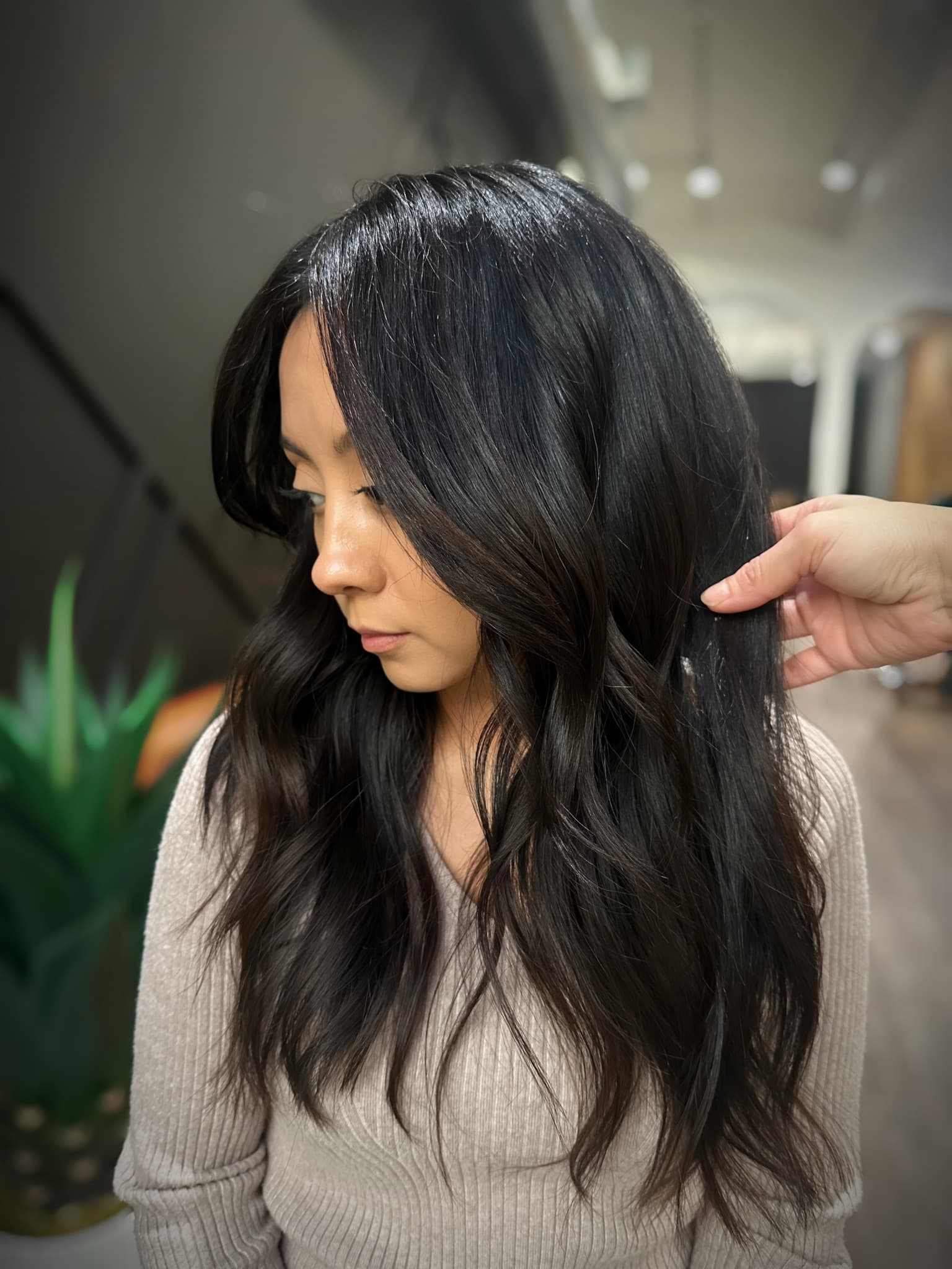 Long layered cut on glossy black hair, lifted to show how the layers fall