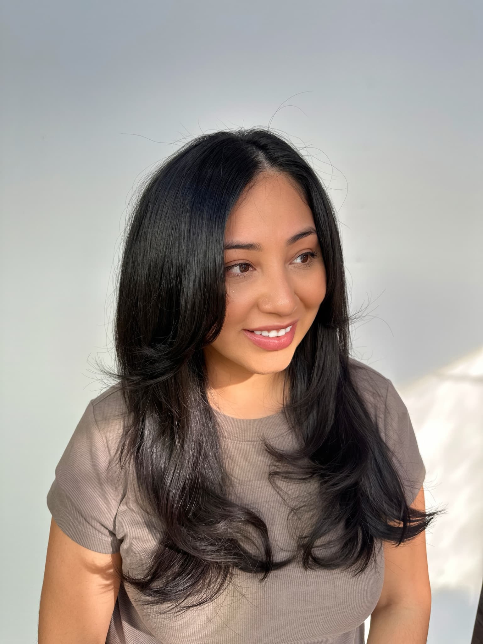 Long black hair with face-framing layers styled with a soft bend through the ends
