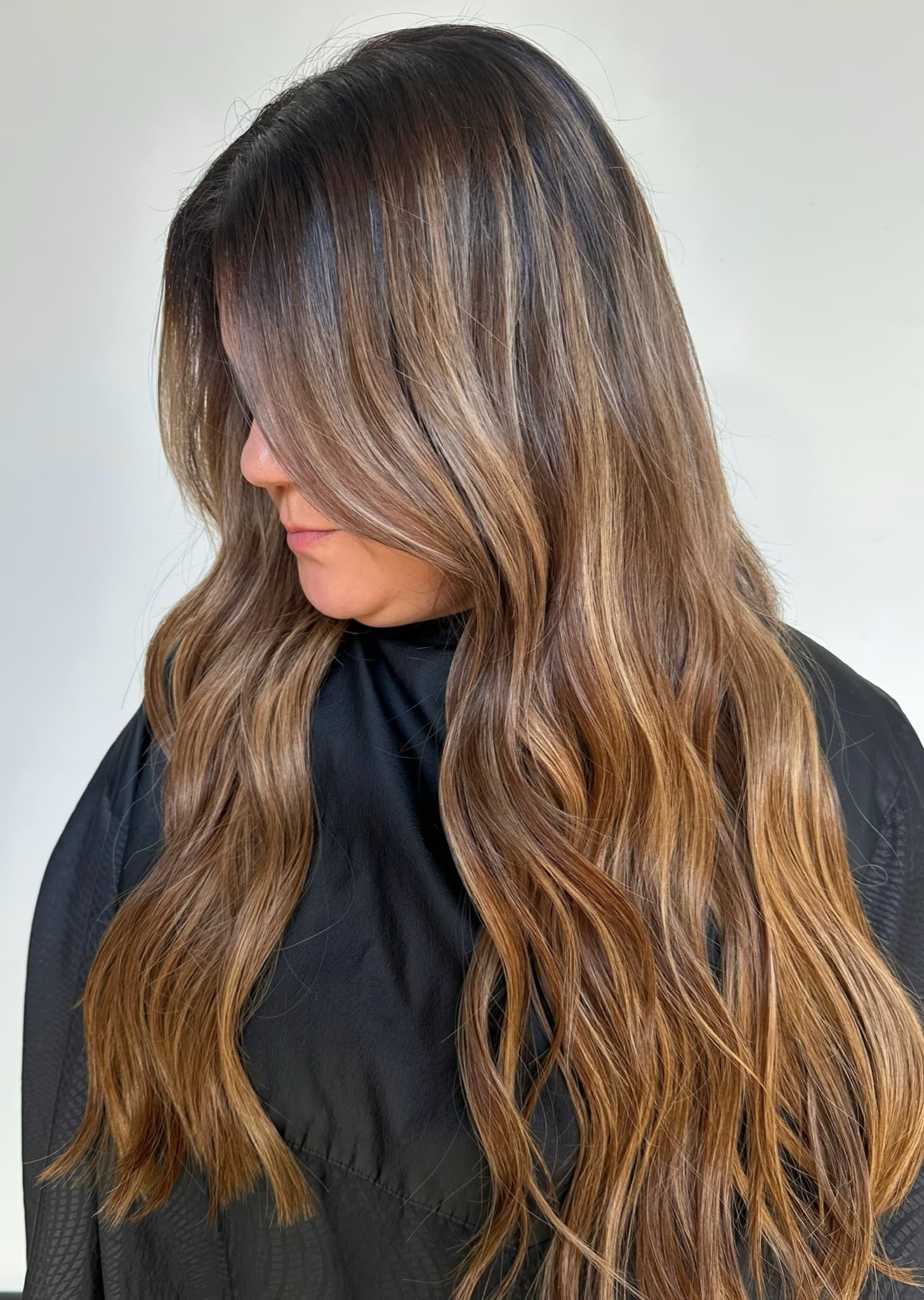 Caramel balayage on long, wavy extensions falling well past the shoulders