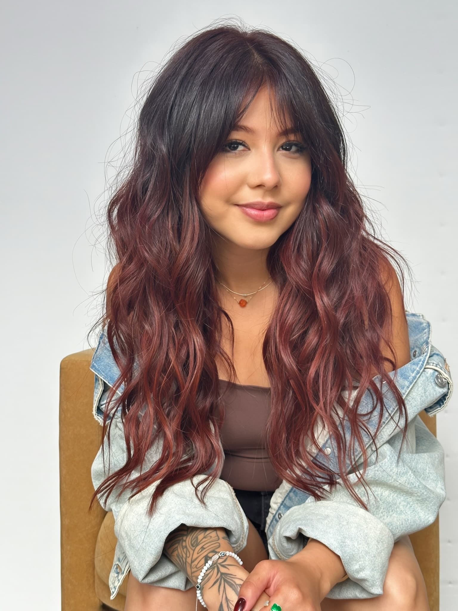 Client with burgundy waves and curtain bangs after an extension install