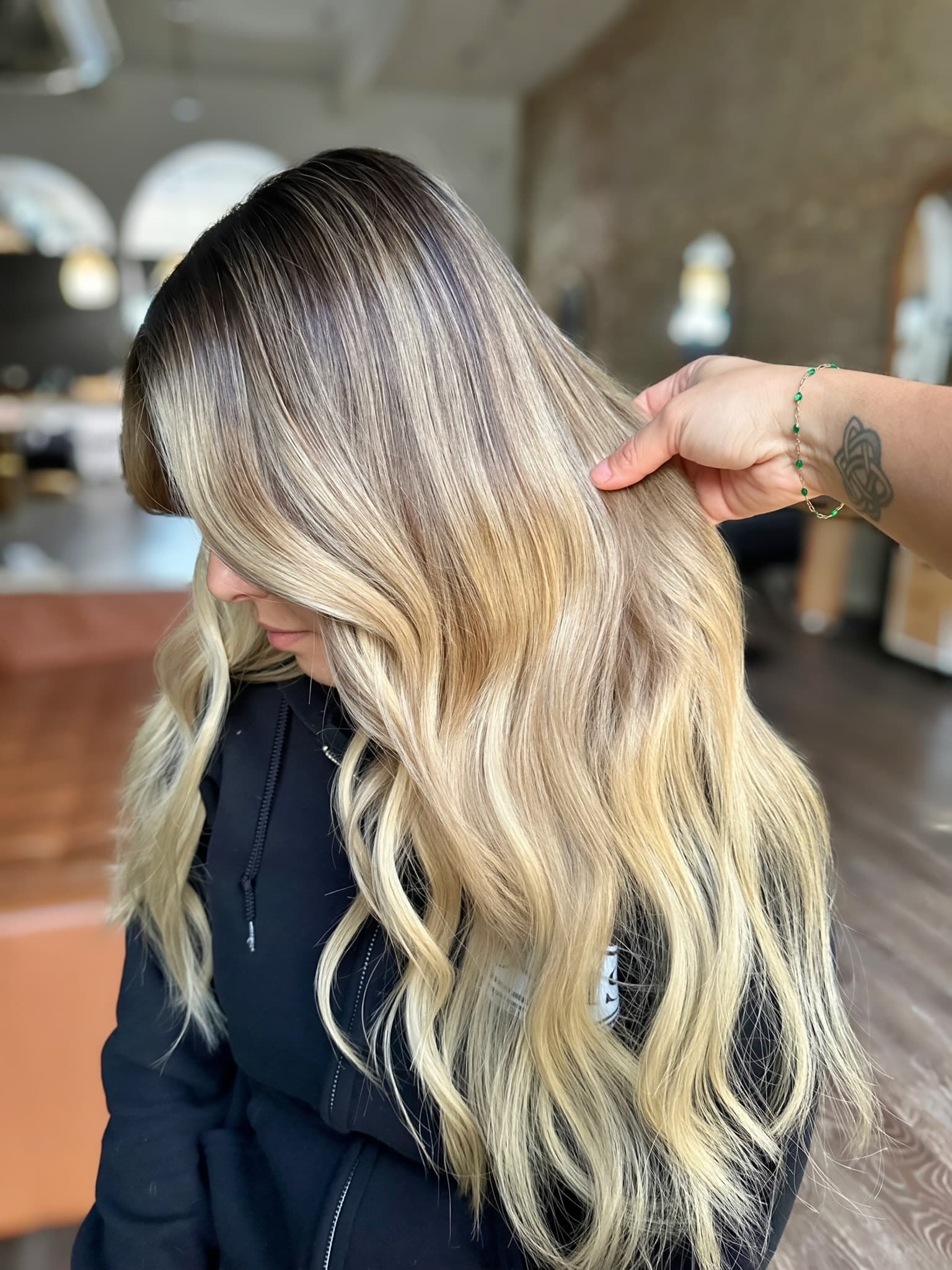 Blonde balayage extensions held up to show the seamless color blend